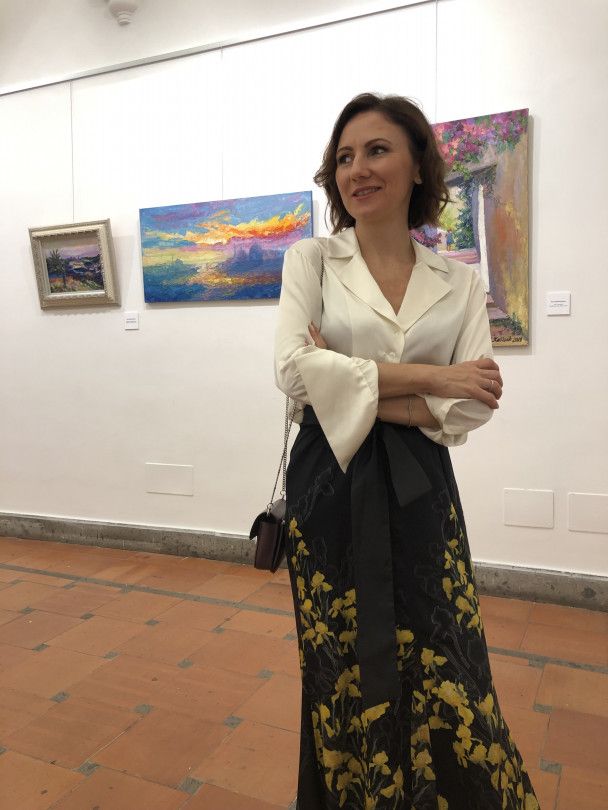 Inna Katyushchenko on the background of her paintings