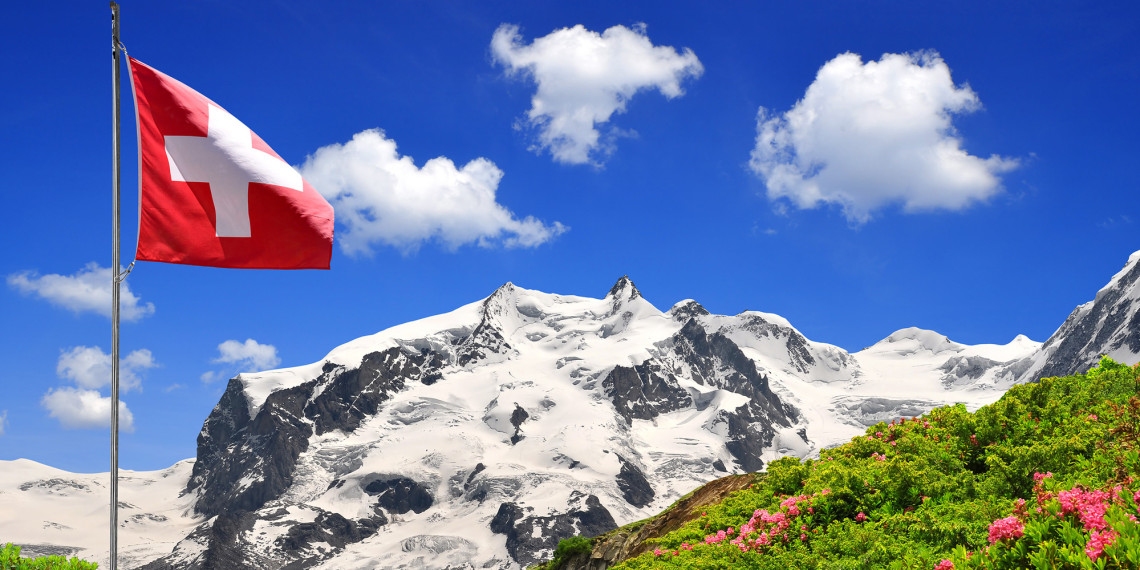 Swiss flag in front of mountains