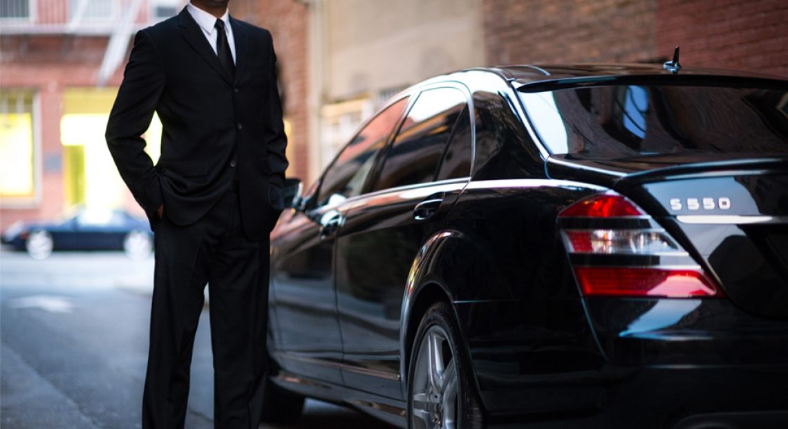 man in black suit near black car