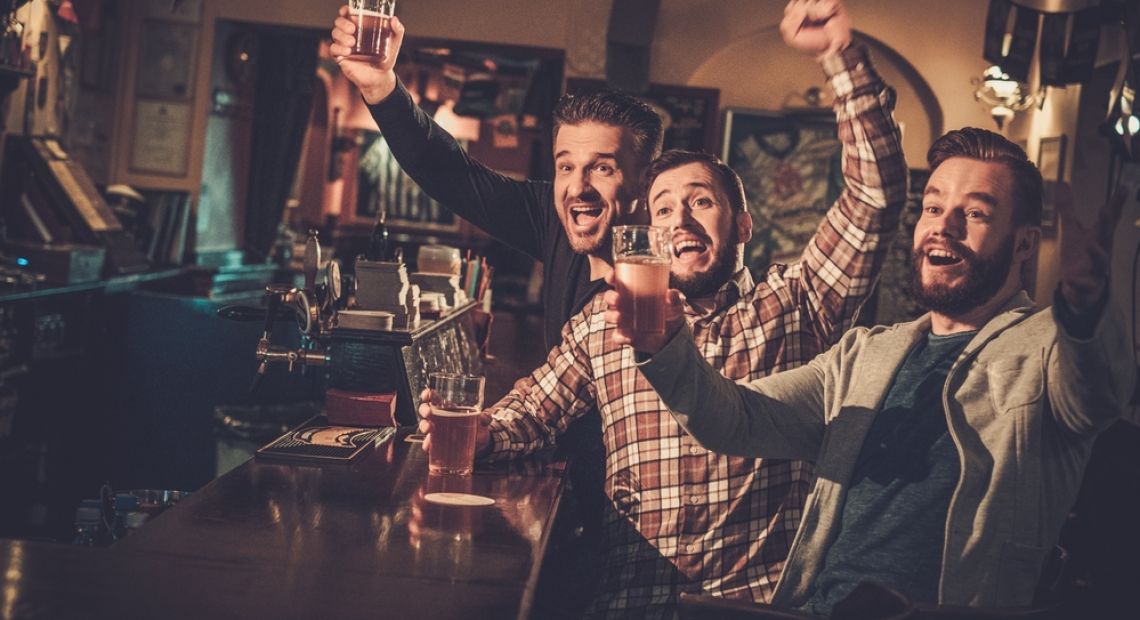 three men drinking beer and having fun in pub