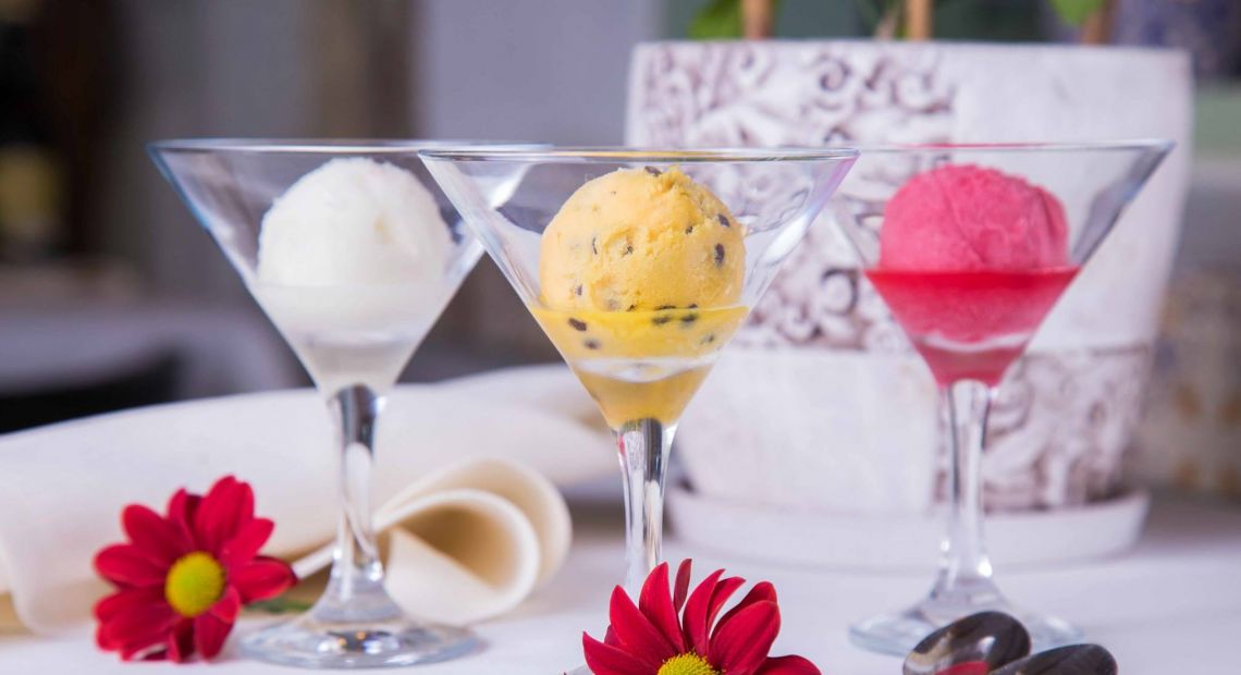 red flowers and three glasses with ice cream on table