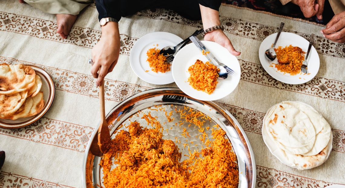 female hands stirring rice and putting it on plates on served table with plate with flatbreads