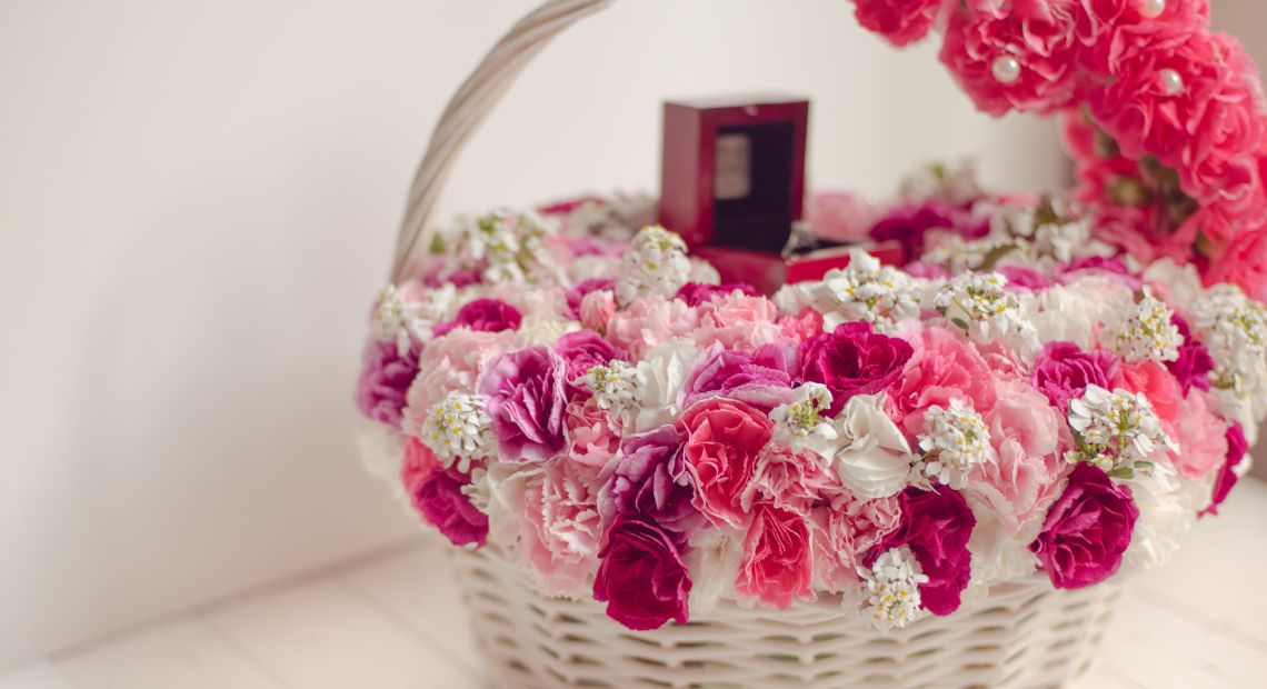 white basket with pink and white flowers and small gift box