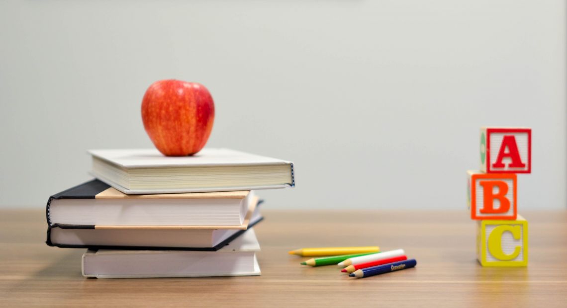 A pile of books with an apple and ABC