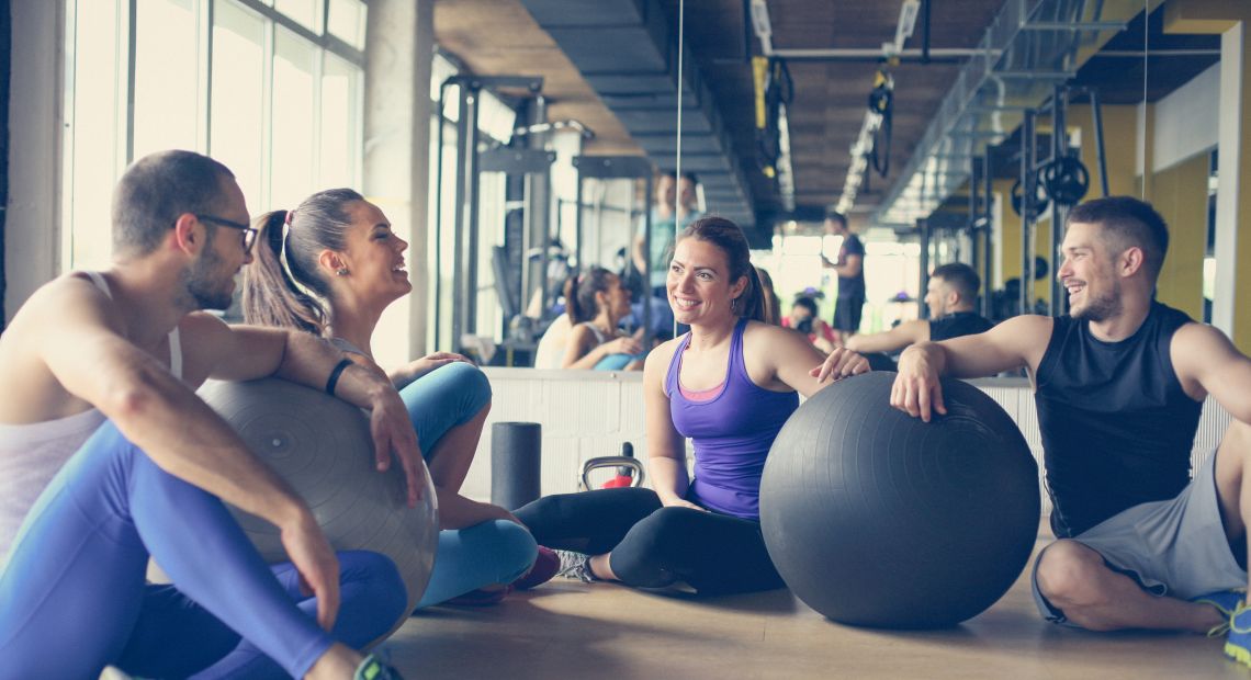 group of people near fitballs having conversation in gym