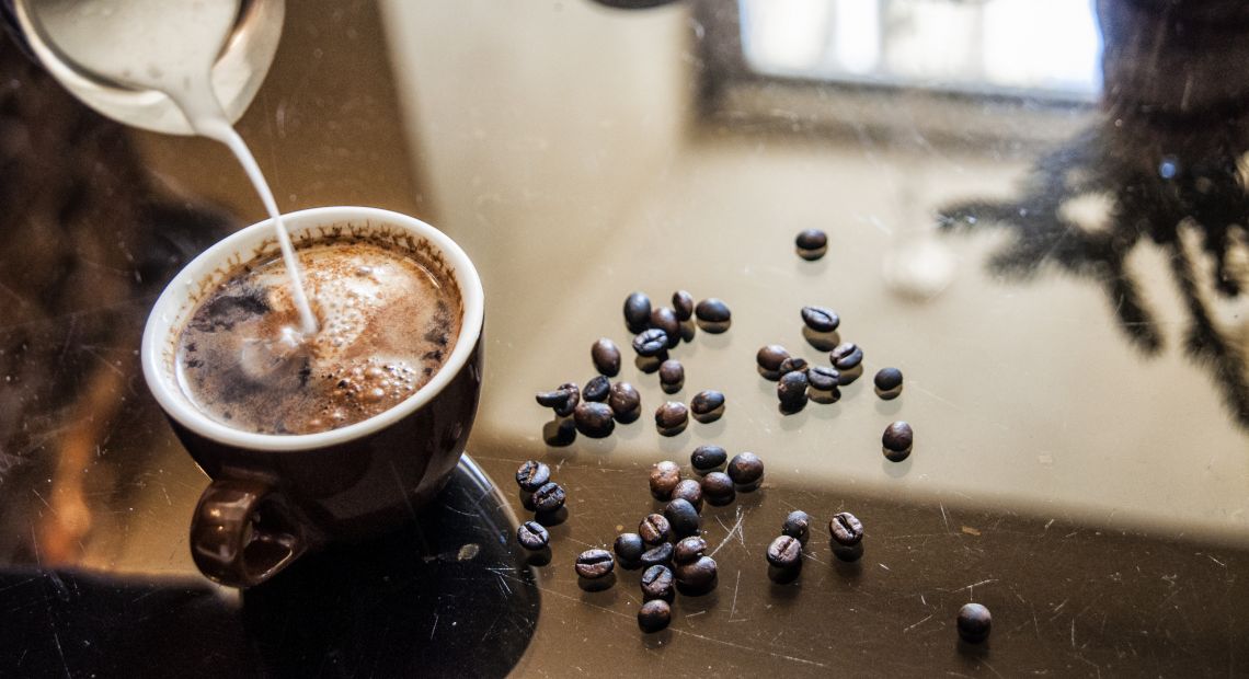 Cup of coffee with milk and coffee beans