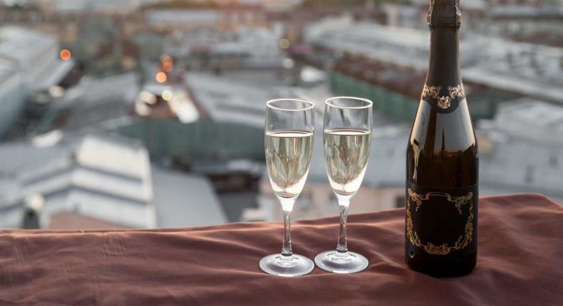 A bottle of champagne with two glasses on a rooftop