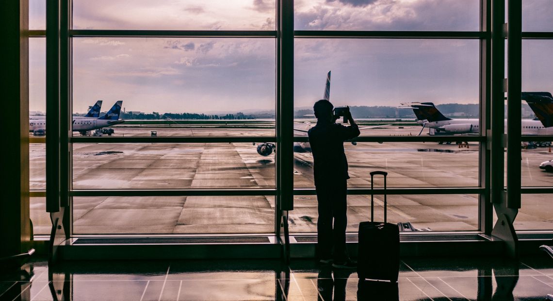Man taking a picture of an airplane in an airport