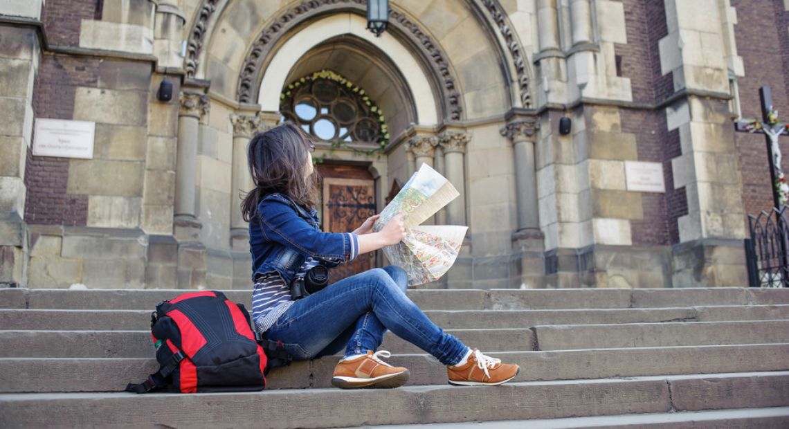 Tourist girl with a map looking at a cathedral