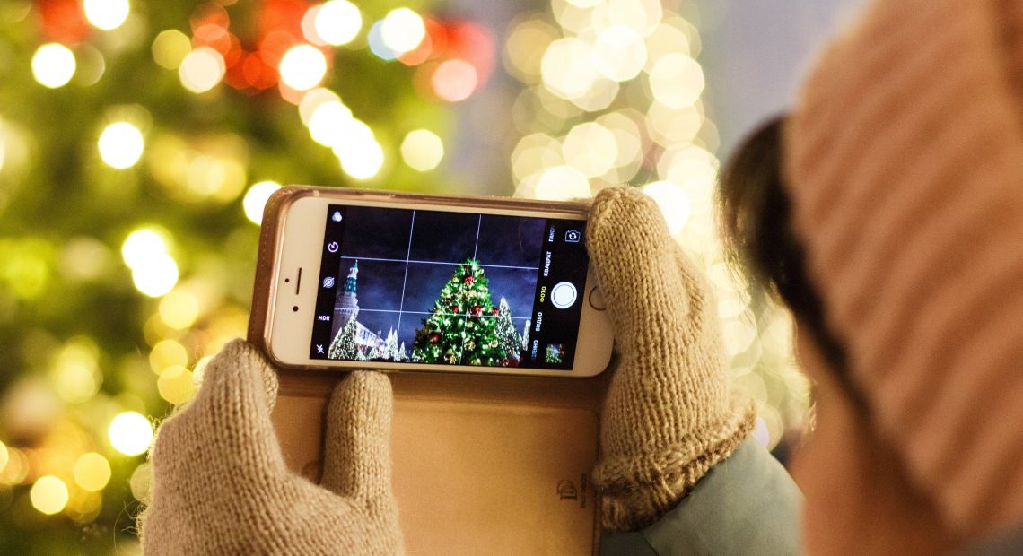 Person holding a phone and taking a pic of a Christmas tree