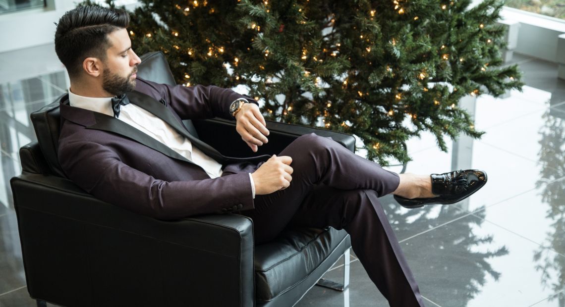Man in a suit sitting by the Christmas tree