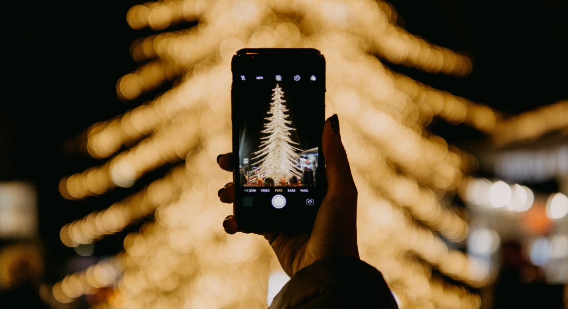 hand holding smartphone taking a photo of christmas tree