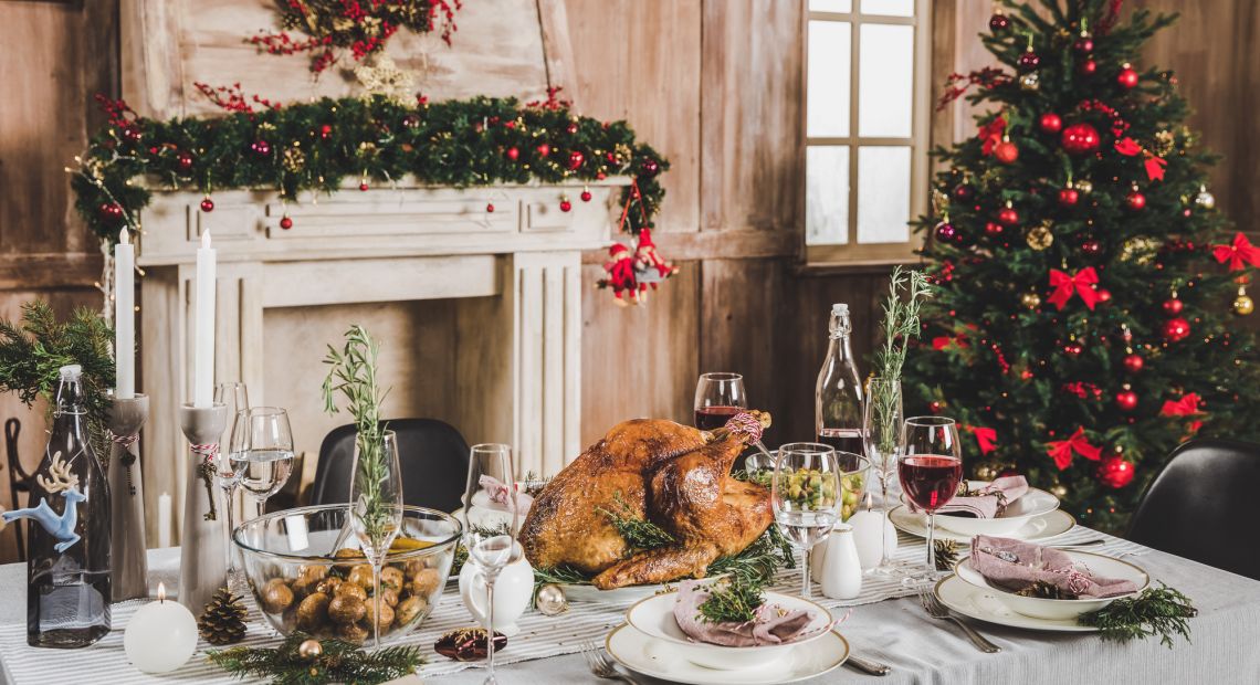 festive Christmas table with dinner near decorated fireplace and Christmas tree