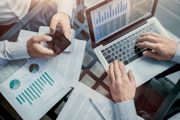 hands of two businessman over documents working with smartphone and laptop