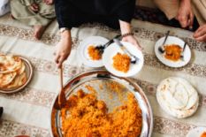 female hands stirring rice and putting it on plates on served table with plate with flatbreads
