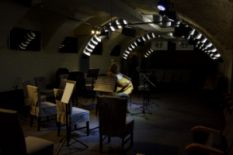 musician playing on string instrument in dark concert hall with chairs