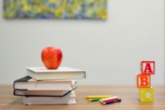 A pile of books with an apple and ABC