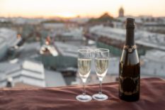 A bottle of champagne with two glasses on a rooftop