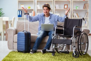 man with wheelchair and laptop in hotel room
