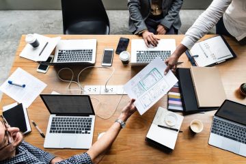 people around table with laptops and documents