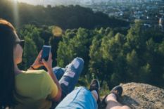 two people sitting on mountain with smart phone