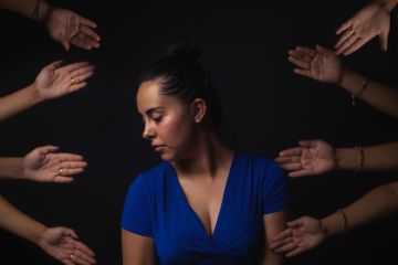 woman surrounded bu human hands