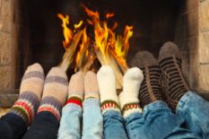 four pairs of legs in socks in front of fireplace