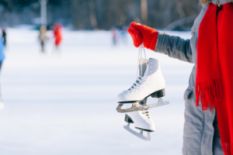 Person in red mittens holding ice skates