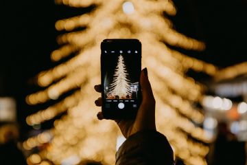 hand holding smartphone taking a photo of christmas tree