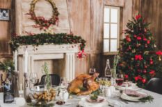 festive Christmas table with dinner near decorated fireplace and Christmas tree
