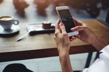 female hands holding smartphone in coffee shop