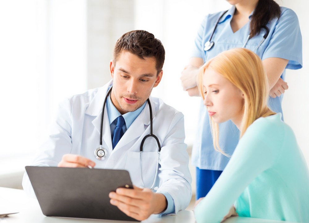 doctor looking at laptop and talking to patient