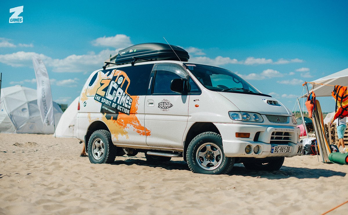 car with festival logo on sand with tents on background