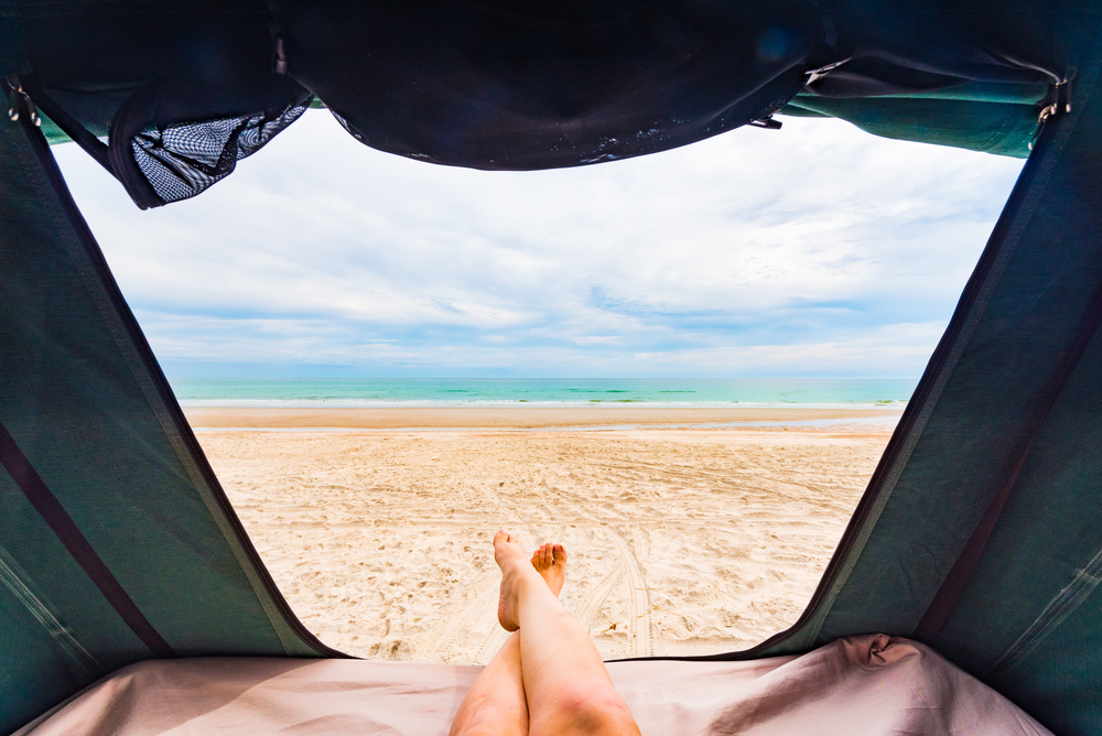 lady's feet out of tent on the beach