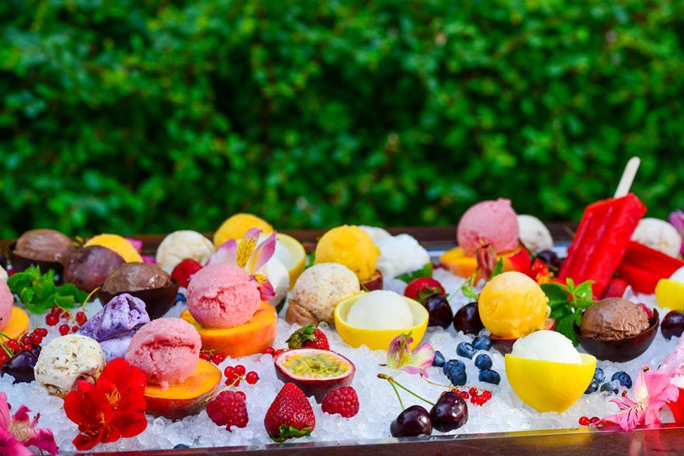 fruits and ice cream scoops in box with ice with greenery on background