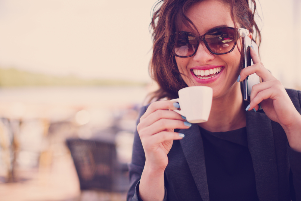 woman holding coffee cup and talking on mobile phone