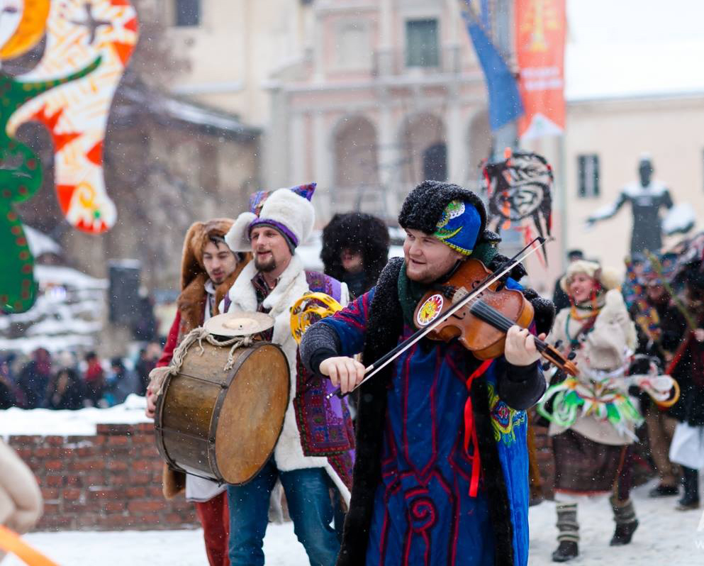 people in christmas clothes singing carols with music instruments