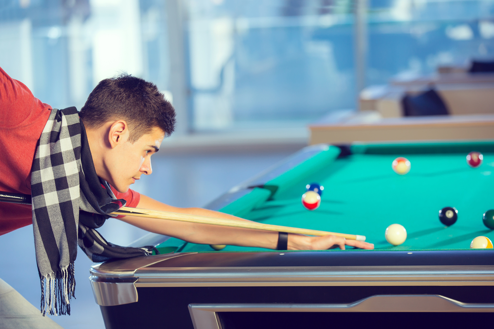 Young dude playing billiards