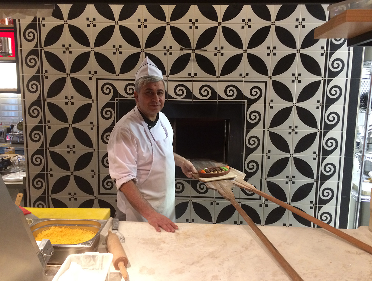 cook in restaurant kitchen holding plate with ready dish