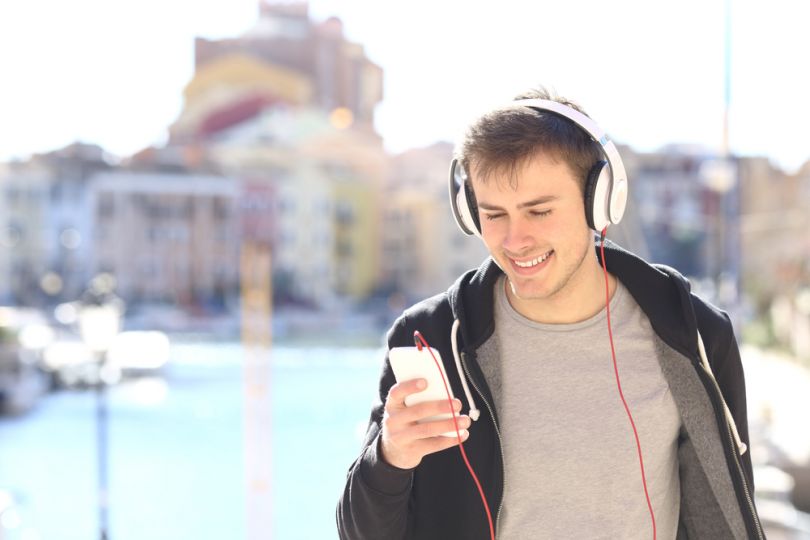young man in street with smartphone in headphones