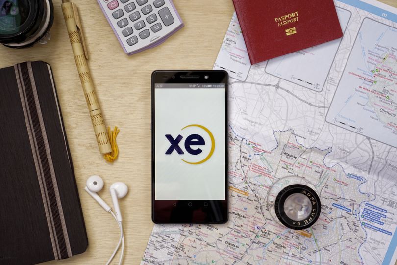 passport, map, caluclator, headphones and smartphone with open XE app