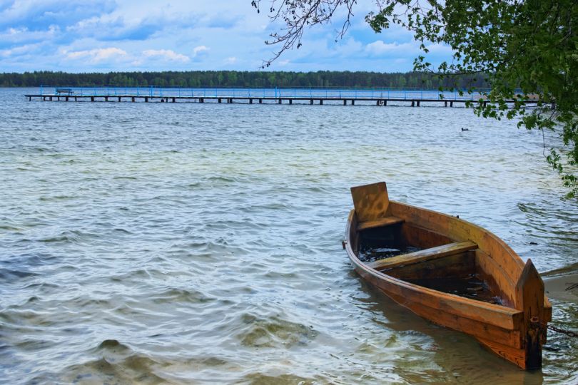 boat on large lake with pier on background