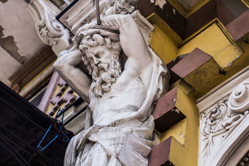 statue of man on below the facade of building