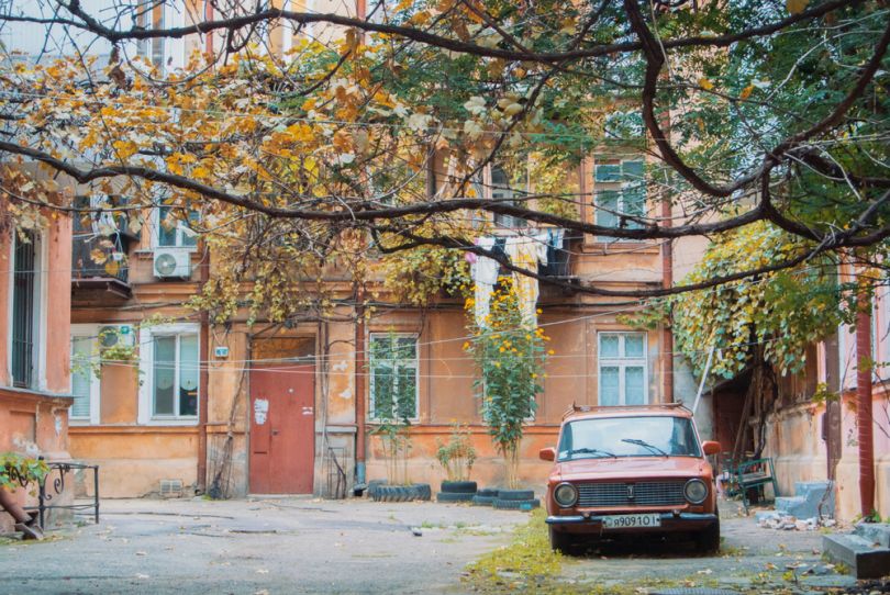 old yard with parked red car