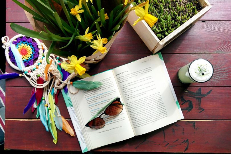book, drink, dreamcatcher, glasses and flowers on table