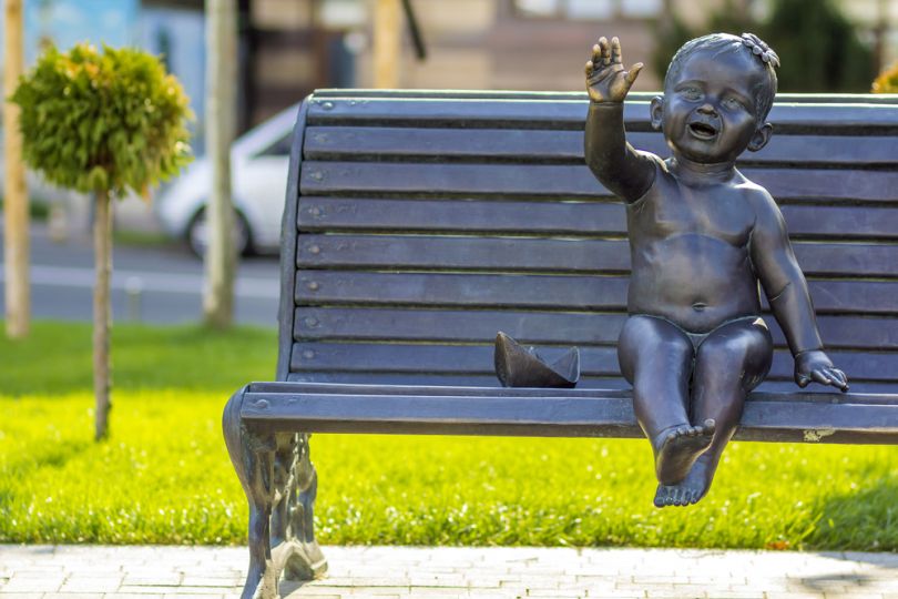 Sculpture of a kid on the bench in Kyiv