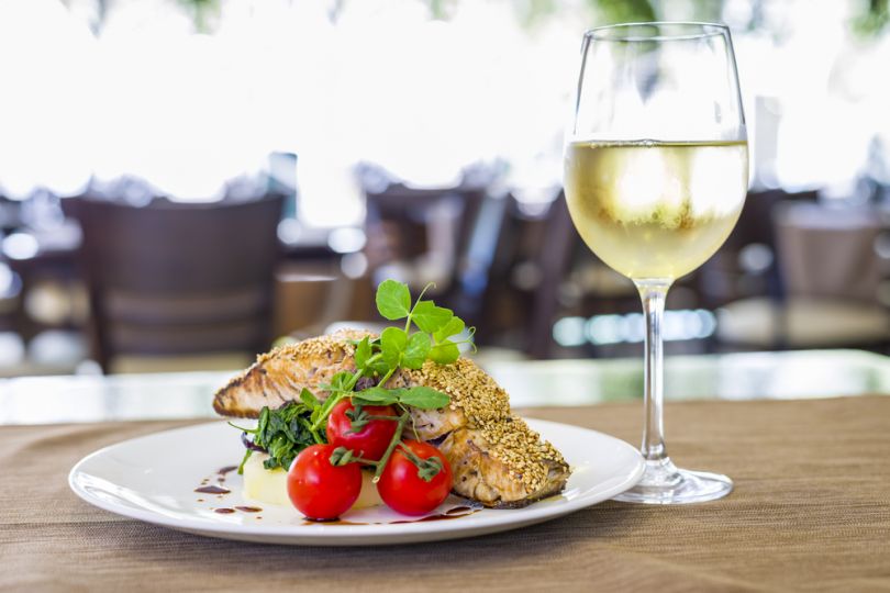 glass of white wine, plate with tomatoes and fish
