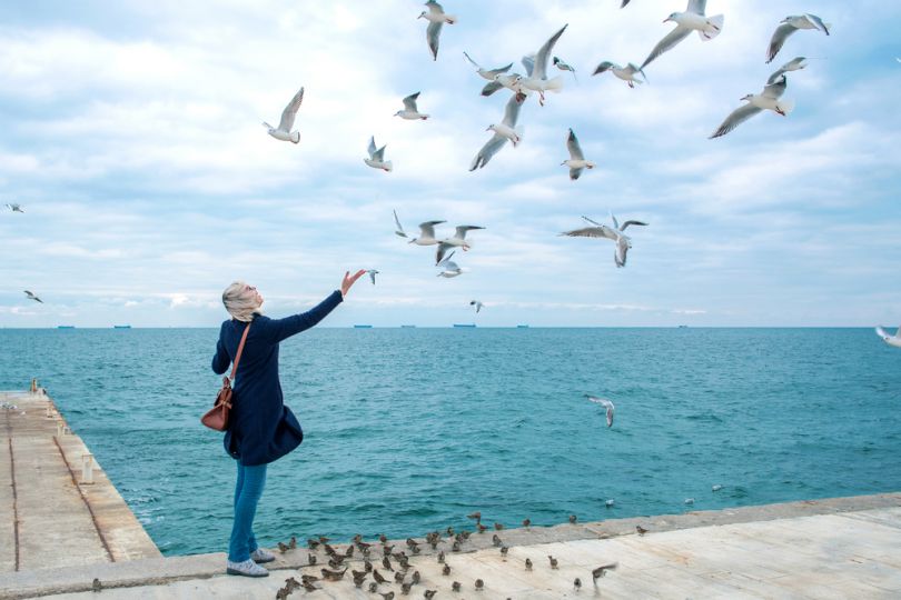 Woman feeding birds on a beach in Odesa