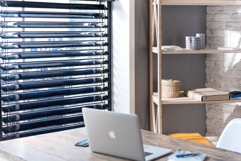 window with blinds and table with laptop