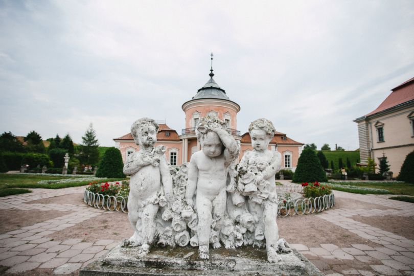 statue of three cupids with castle on background